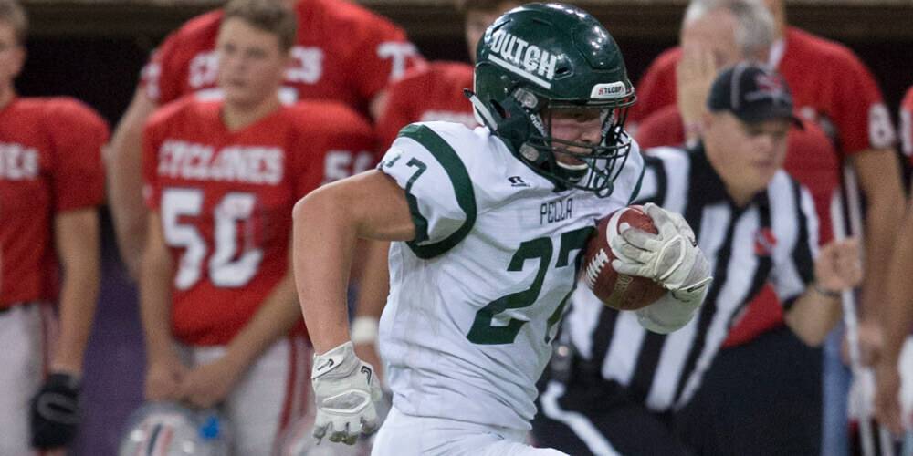 Pella football player running with the ball