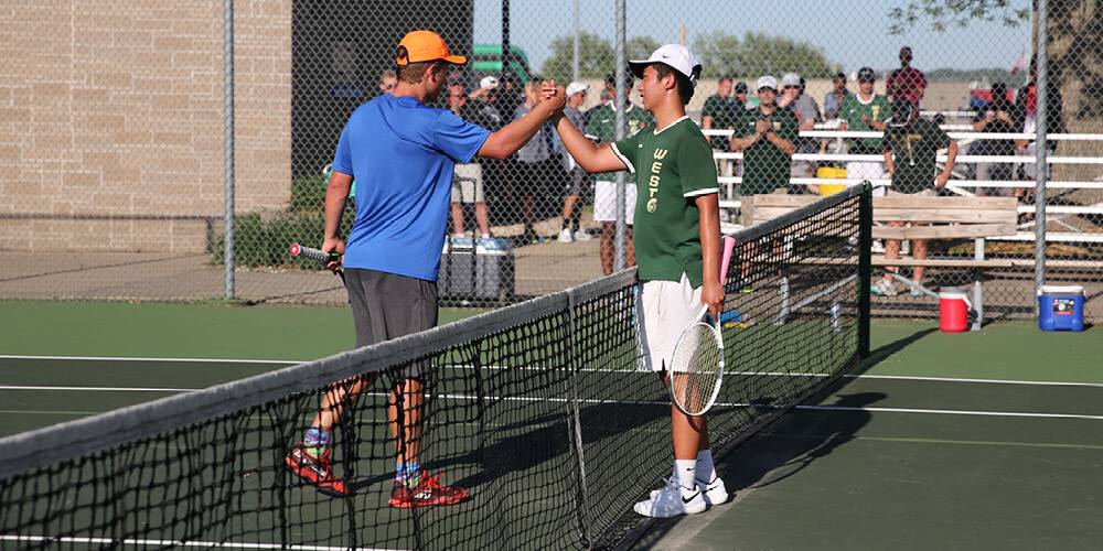 Two players shake hands over the net during a tennis match