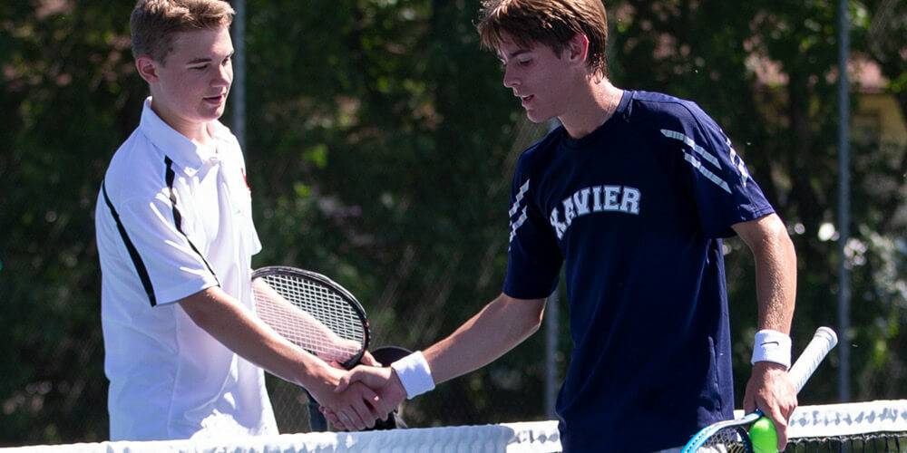 Two tennis players shaking hands across the net