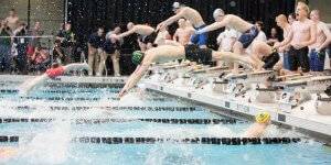 Swimmers diving into the water at a meet
